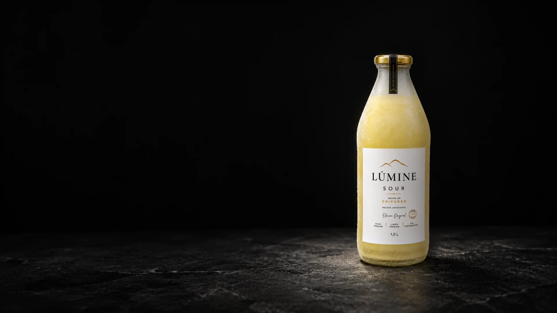 Botella de Lúmine Sour fría y escarchada sobre una piedra oscura